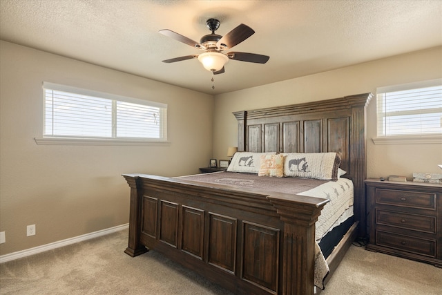 bedroom featuring ceiling fan, a textured ceiling, multiple windows, and light colored carpet