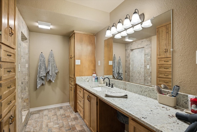 2720 N US-377, Stephenville, TX 76401 - bathroom with vanity, a tile shower, baseboards, a textured ceiling, and brick floor