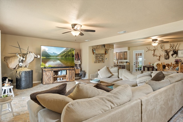 living room with a textured ceiling and ceiling fan