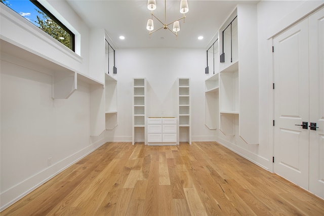 spacious closet with a chandelier and light wood-type flooring