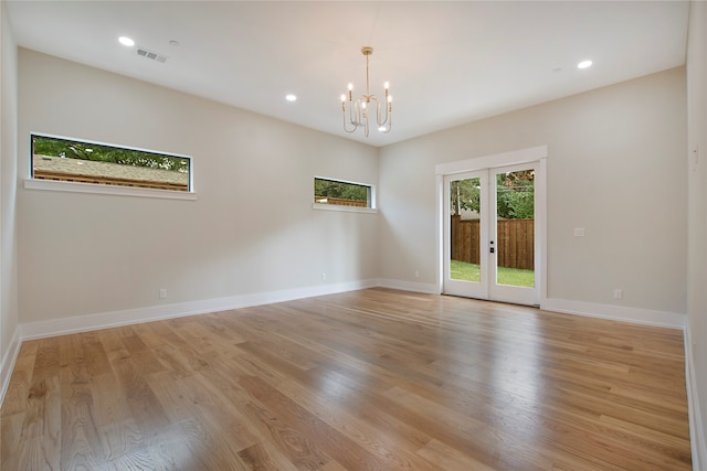 unfurnished room with french doors, light hardwood / wood-style floors, and an inviting chandelier