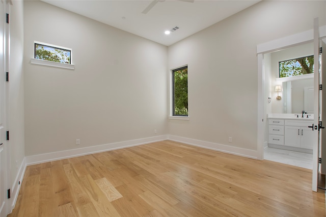 unfurnished bedroom featuring light hardwood / wood-style floors, multiple windows, and ensuite bathroom