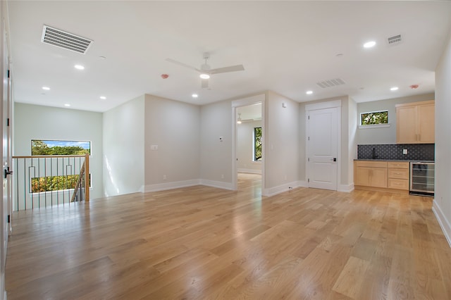 unfurnished living room with wine cooler, light hardwood / wood-style flooring, and ceiling fan