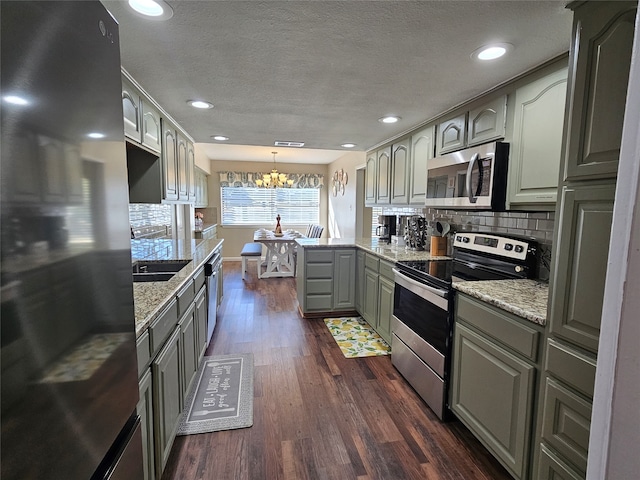 kitchen featuring gray cabinetry, backsplash, stainless steel appliances, pendant lighting, and dark hardwood / wood-style floors