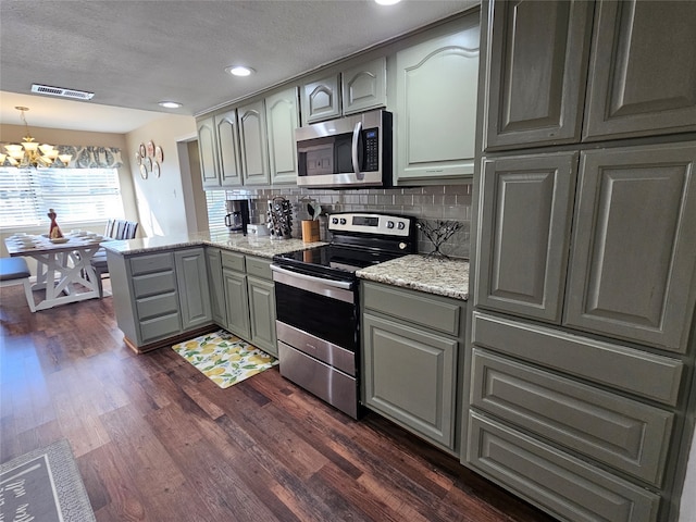 kitchen featuring dark wood-type flooring, gray cabinetry, stainless steel appliances, a notable chandelier, and decorative light fixtures