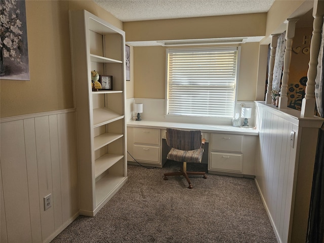 office with built in desk, a textured ceiling, and carpet floors