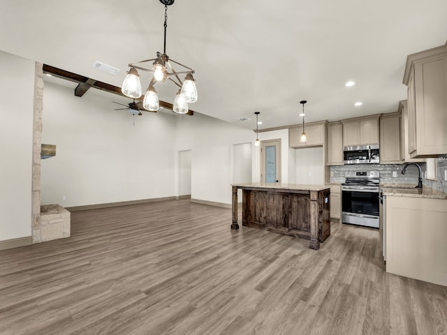 kitchen with backsplash, hardwood / wood-style flooring, stainless steel appliances, decorative light fixtures, and a center island