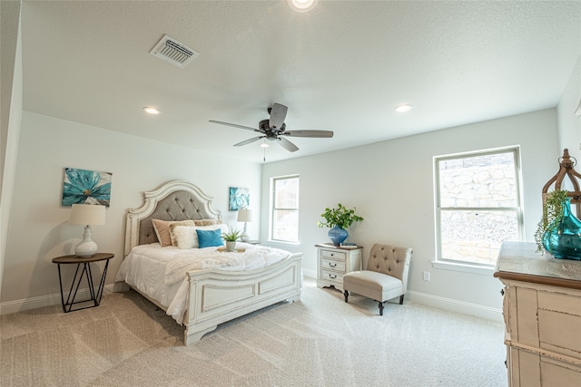 carpeted bedroom featuring ceiling fan, a textured ceiling, and multiple windows