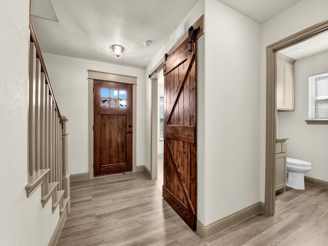 entryway with a textured ceiling, a barn door, and light wood-type flooring