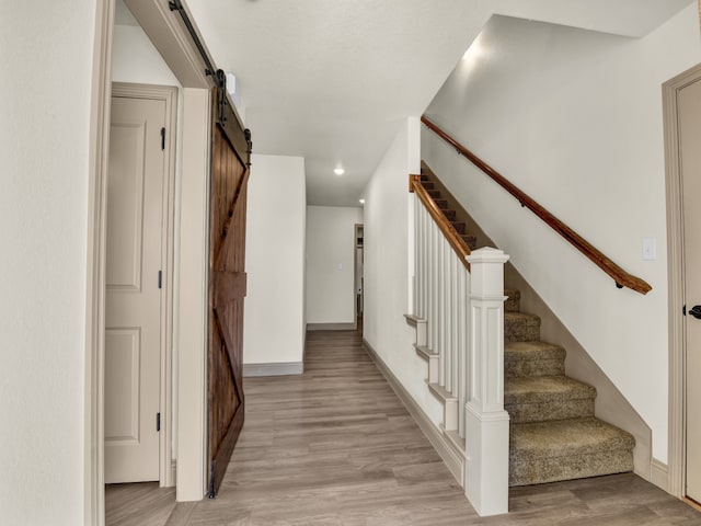 stairway with a barn door and hardwood / wood-style floors