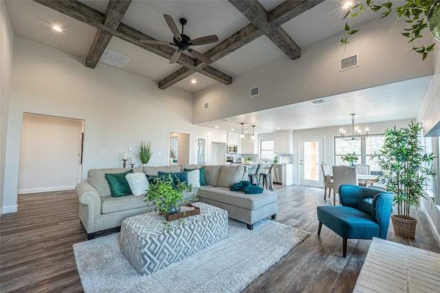 living room featuring hardwood / wood-style floors, beam ceiling, a high ceiling, ceiling fan with notable chandelier, and coffered ceiling