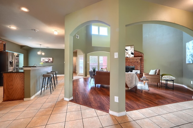 foyer with light hardwood / wood-style flooring, a high ceiling, a notable chandelier, and a fireplace