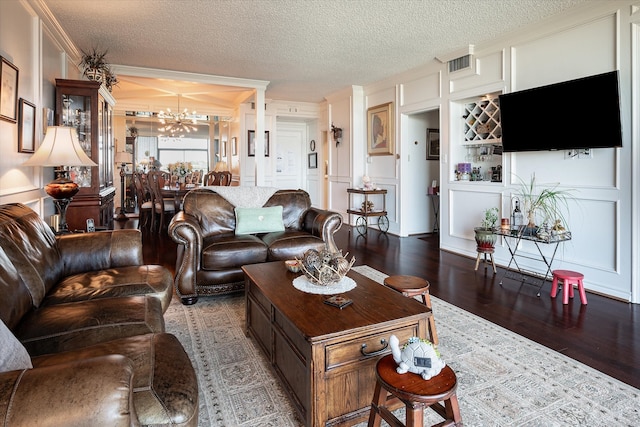 living room with a textured ceiling, ornamental molding, a chandelier, and hardwood / wood-style floors