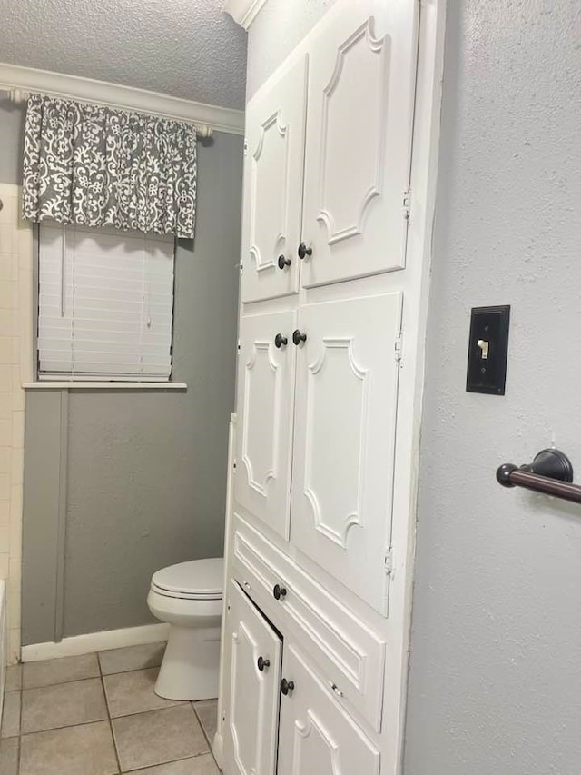 bathroom with toilet, tile patterned floors, and a textured ceiling