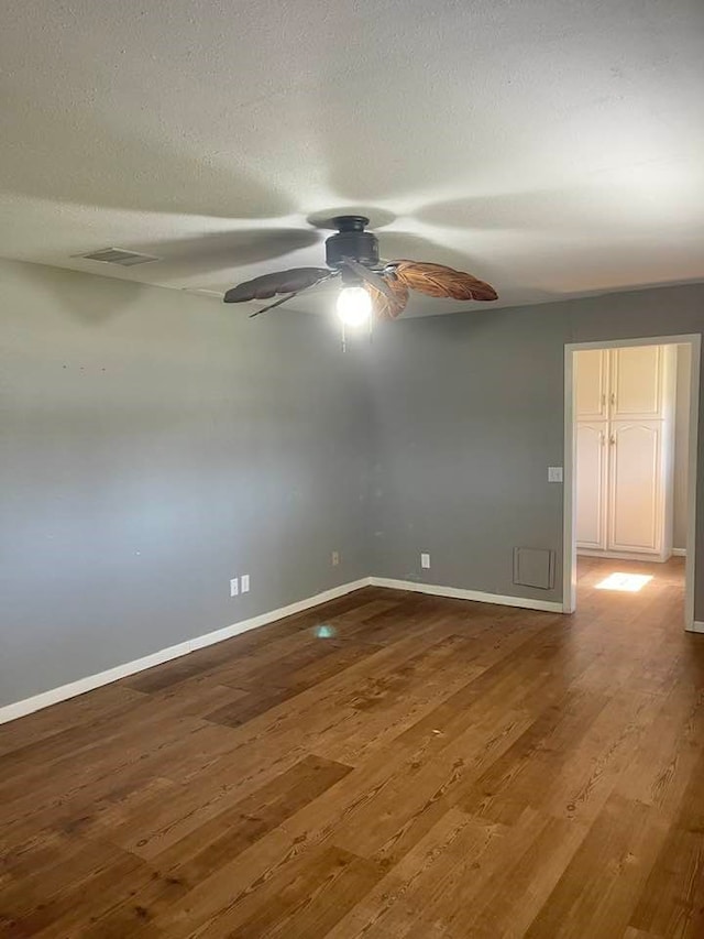 empty room with a textured ceiling, wood-type flooring, and ceiling fan