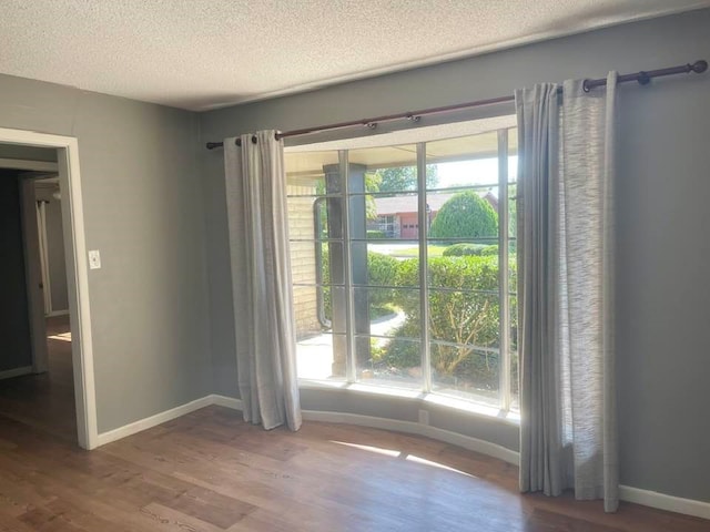 spare room featuring hardwood / wood-style flooring, a textured ceiling, and plenty of natural light