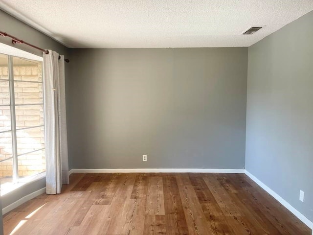 unfurnished room featuring hardwood / wood-style flooring and a textured ceiling