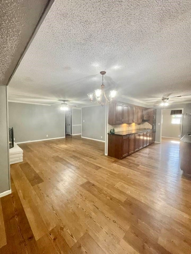 unfurnished living room featuring light hardwood / wood-style floors, a textured ceiling, and ceiling fan with notable chandelier