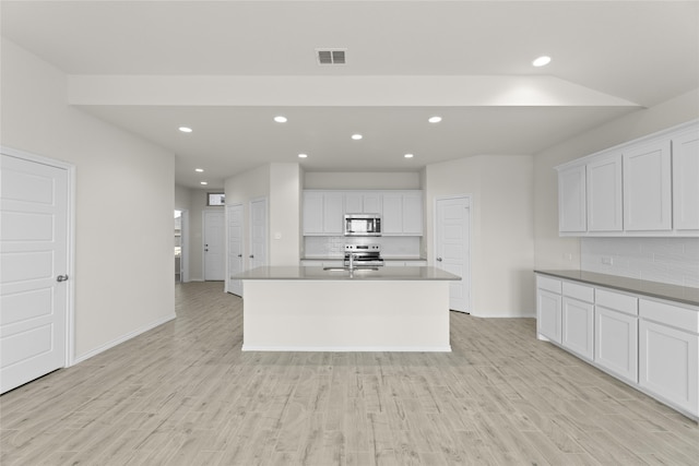 kitchen with appliances with stainless steel finishes, light wood-type flooring, tasteful backsplash, and white cabinetry