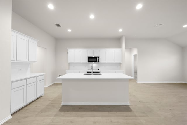 kitchen featuring a center island with sink, light hardwood / wood-style floors, white cabinetry, and sink