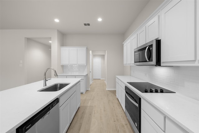 kitchen featuring sink, light hardwood / wood-style flooring, tasteful backsplash, white cabinetry, and stainless steel appliances