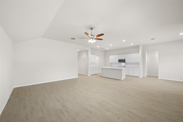 unfurnished living room featuring ceiling fan, sink, light hardwood / wood-style floors, and lofted ceiling