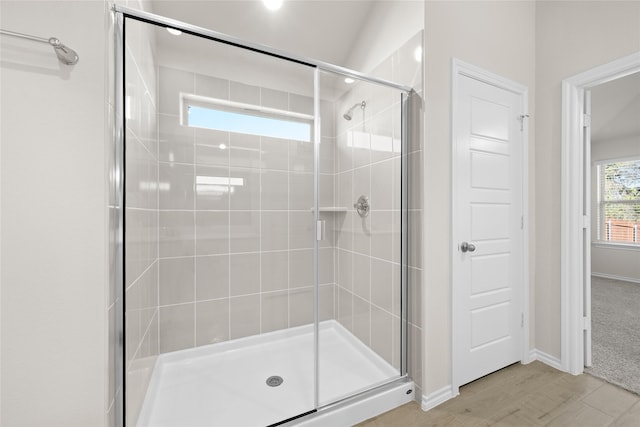 bathroom featuring a shower with door, vaulted ceiling, and hardwood / wood-style flooring