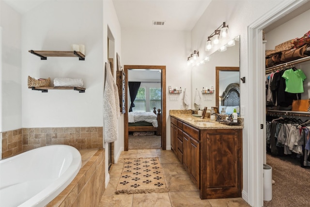 bathroom featuring tiled tub and vanity