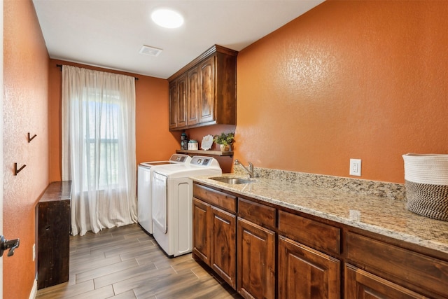 washroom featuring sink, washer and dryer, and cabinets