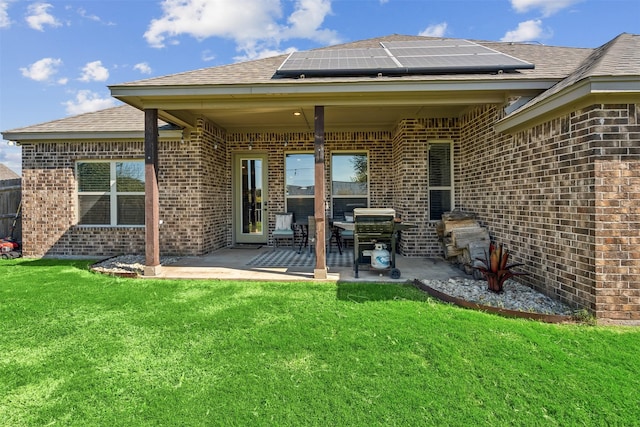 back of house with a yard, a patio area, and solar panels