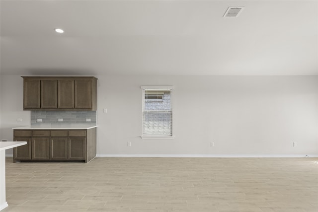 kitchen featuring decorative backsplash, dark brown cabinetry, and light hardwood / wood-style flooring