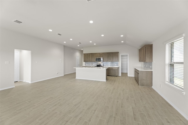 kitchen with appliances with stainless steel finishes, vaulted ceiling, light hardwood / wood-style flooring, and sink