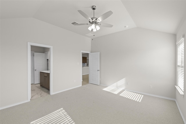 unfurnished bedroom featuring lofted ceiling, ensuite bathroom, ceiling fan, and light colored carpet