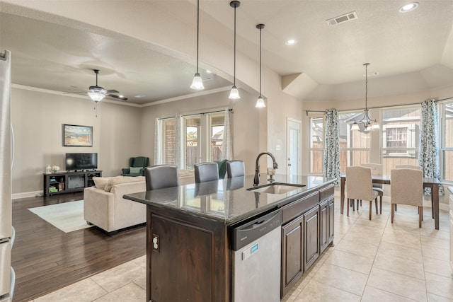 kitchen featuring dishwasher, sink, a healthy amount of sunlight, light hardwood / wood-style floors, and a center island with sink