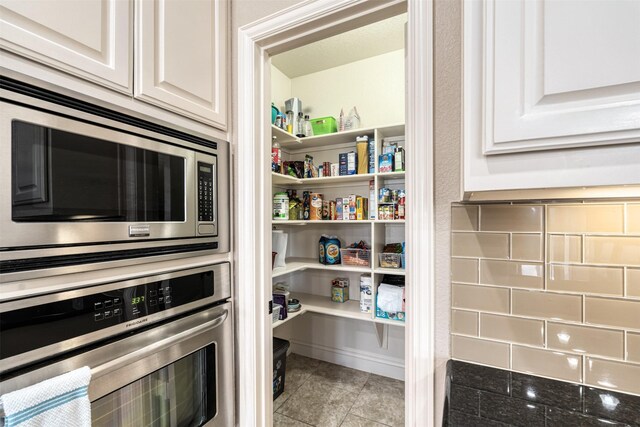 kitchen featuring appliances with stainless steel finishes, sink, white cabinets, light hardwood / wood-style floors, and an island with sink