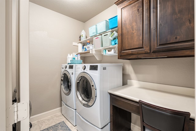 clothes washing area with cabinets, a textured ceiling, washer and dryer, and light tile patterned flooring