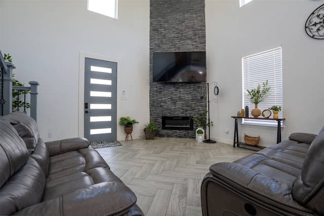 living room with a high ceiling, a fireplace, and light parquet floors