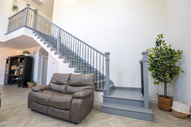 stairway with parquet floors and a towering ceiling