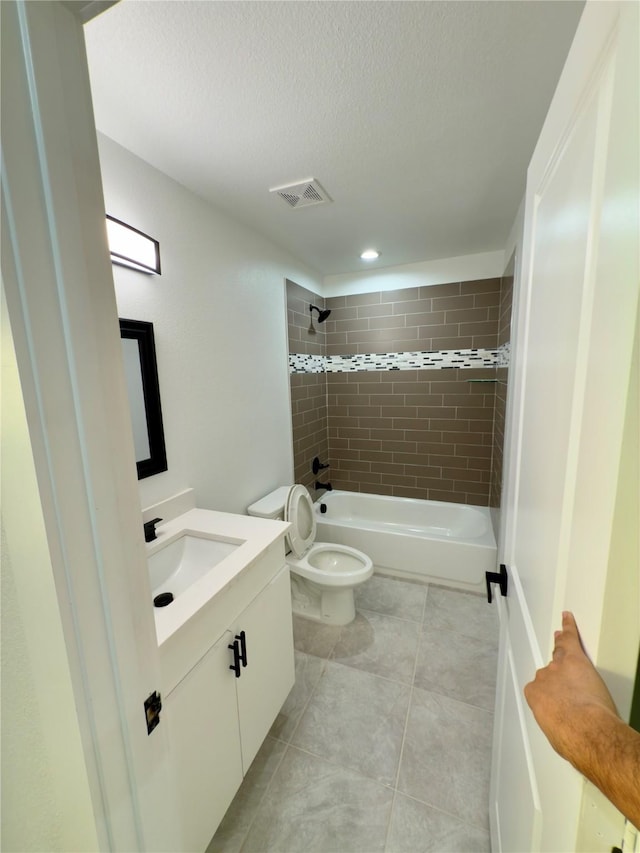 full bathroom featuring toilet, vanity, tiled shower / bath combo, and a textured ceiling