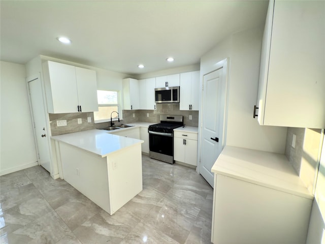 kitchen with white cabinets, stainless steel appliances, tasteful backsplash, sink, and kitchen peninsula