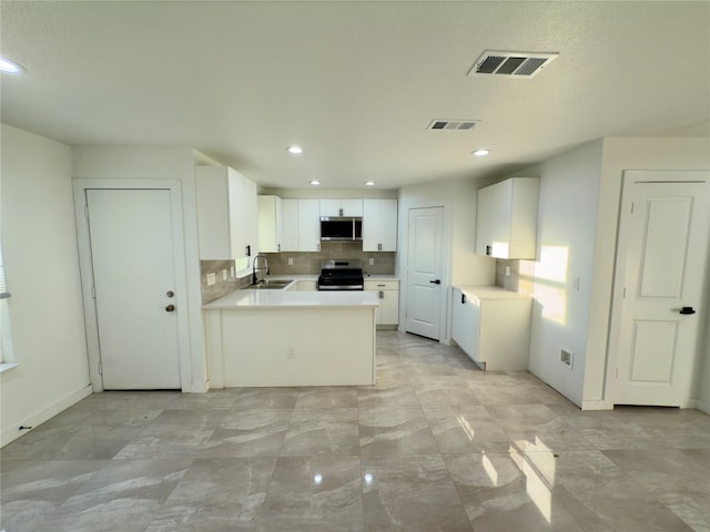 kitchen with backsplash, kitchen peninsula, sink, white cabinetry, and appliances with stainless steel finishes