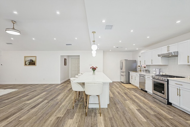 kitchen featuring hanging light fixtures, white cabinetry, sink, light hardwood / wood-style floors, and stainless steel appliances