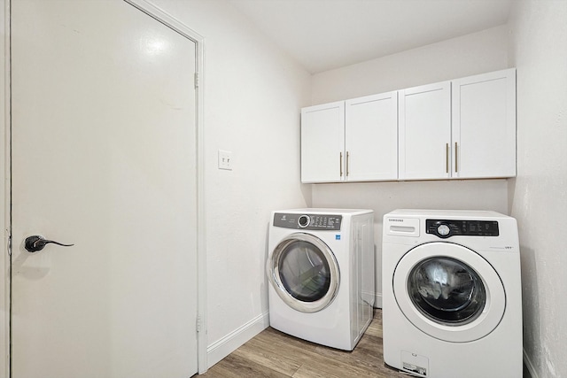 laundry area featuring washer and clothes dryer, light hardwood / wood-style floors, and cabinets