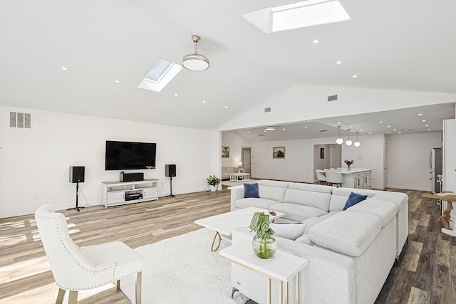 living room with hardwood / wood-style flooring, high vaulted ceiling, and a skylight