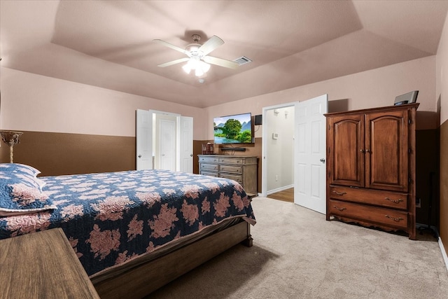 carpeted bedroom with a raised ceiling and ceiling fan