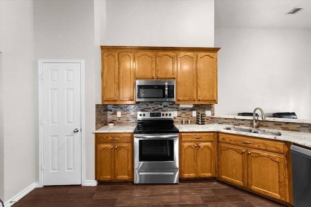 kitchen with light stone countertops, stainless steel appliances, tasteful backsplash, and sink