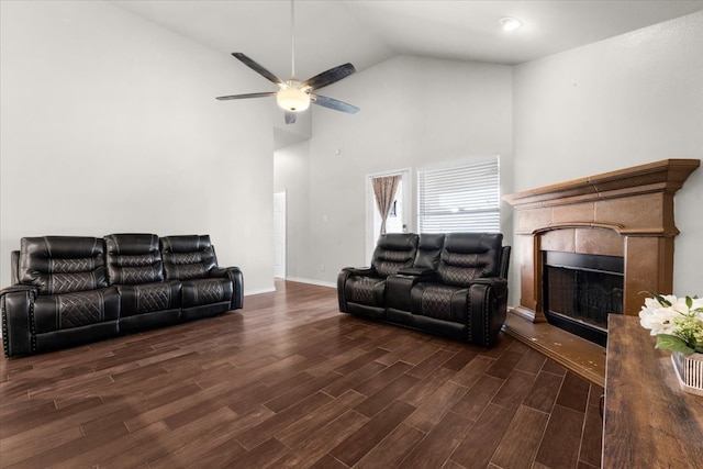 living room featuring ceiling fan, high vaulted ceiling, a tile fireplace, and dark hardwood / wood-style flooring