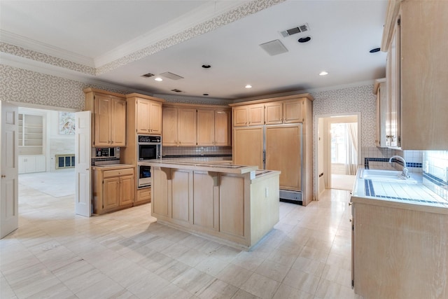 kitchen featuring a kitchen island, a breakfast bar, sink, crown molding, and light brown cabinets