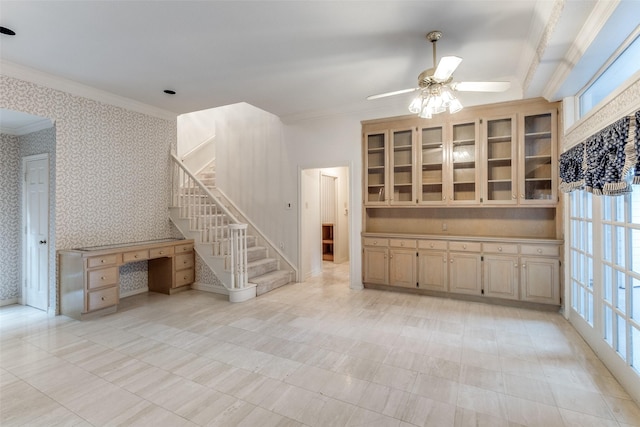 unfurnished living room featuring crown molding, built in desk, and ceiling fan