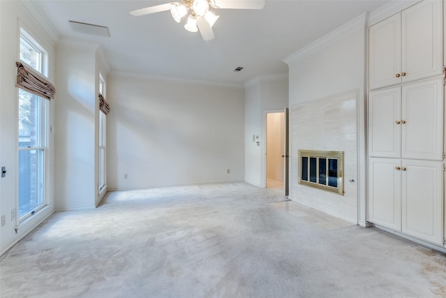 unfurnished living room with ceiling fan, light colored carpet, ornamental molding, and a tiled fireplace